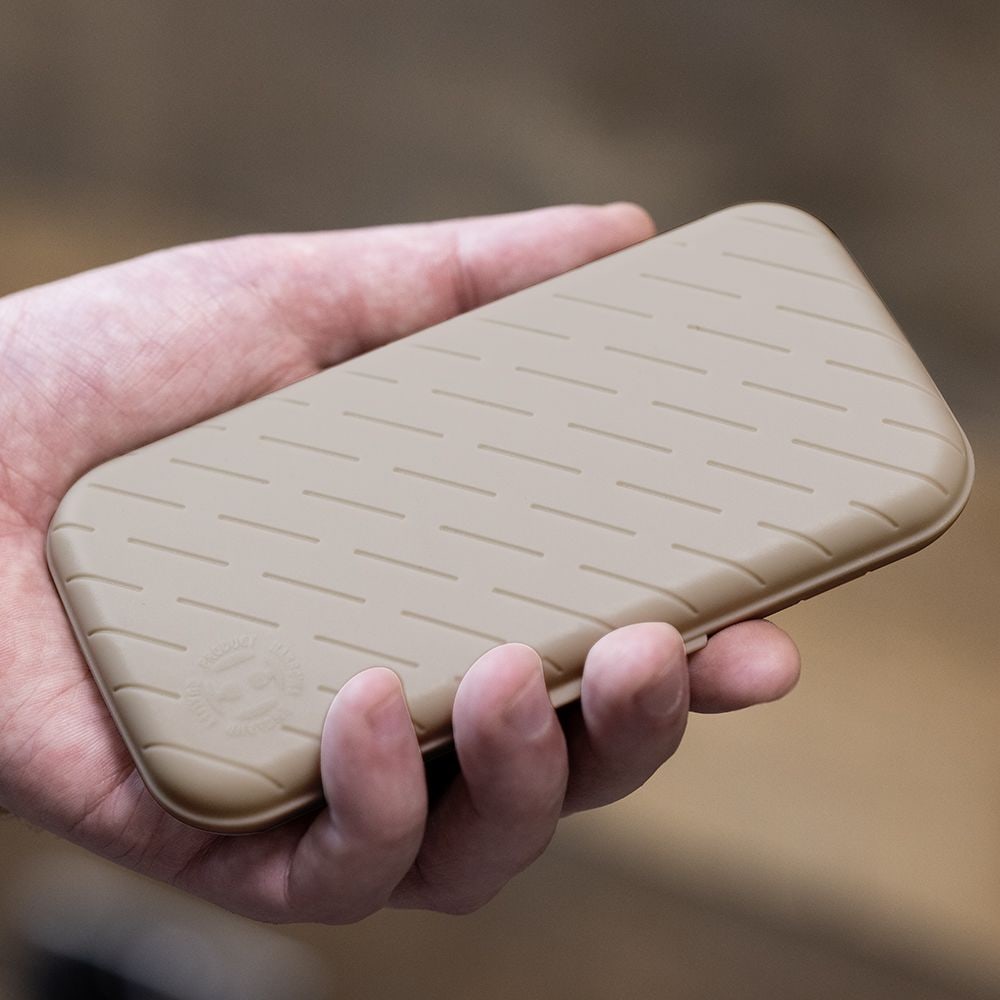Étui à fléchettes Harrows Slimcase Eine Hand hält ein schlankes, steingraues Etui mit einem dezenten Muster. Das Etui wirkt stabil und ist wahrscheinlich für Dartzubehör gedacht.