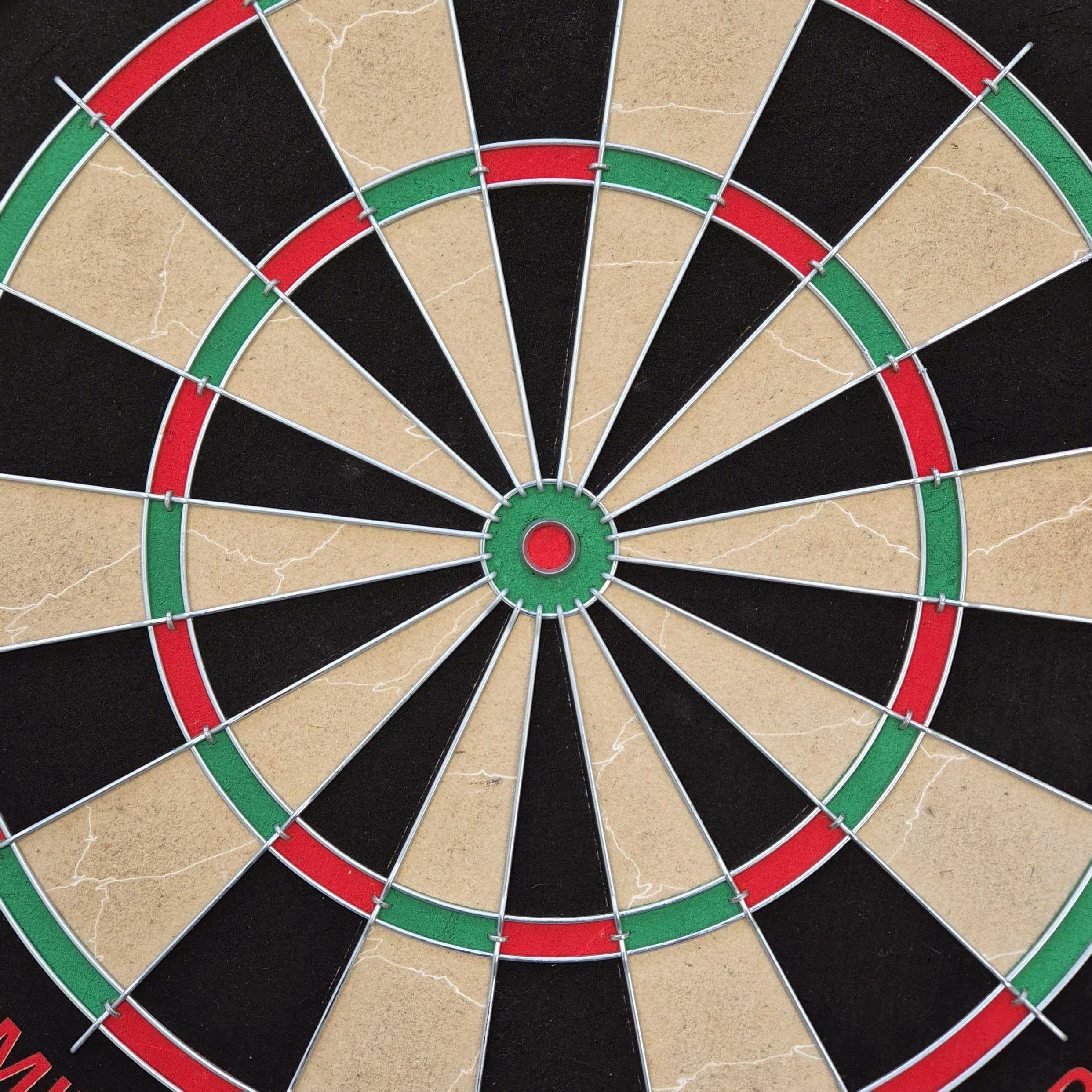 Jeu de fléchettes en acier Target Dimitri Van Den Bergh Auf dem Bild ist eine Steeldartscheibe mit farbigen Segmenten in Rot, Grün, Schwarz und Beige zu sehen. Es handelt sich um das Produkt "Target Dimitri Van Den Bergh Steeldartboard Set".