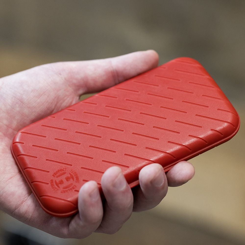 Étui à fléchettes Harrows Slimcase Eine Person hält eine rote, strukturierte Darttasche in der Hand. Die Darttasche hat eine schlanke und kompakte Form.