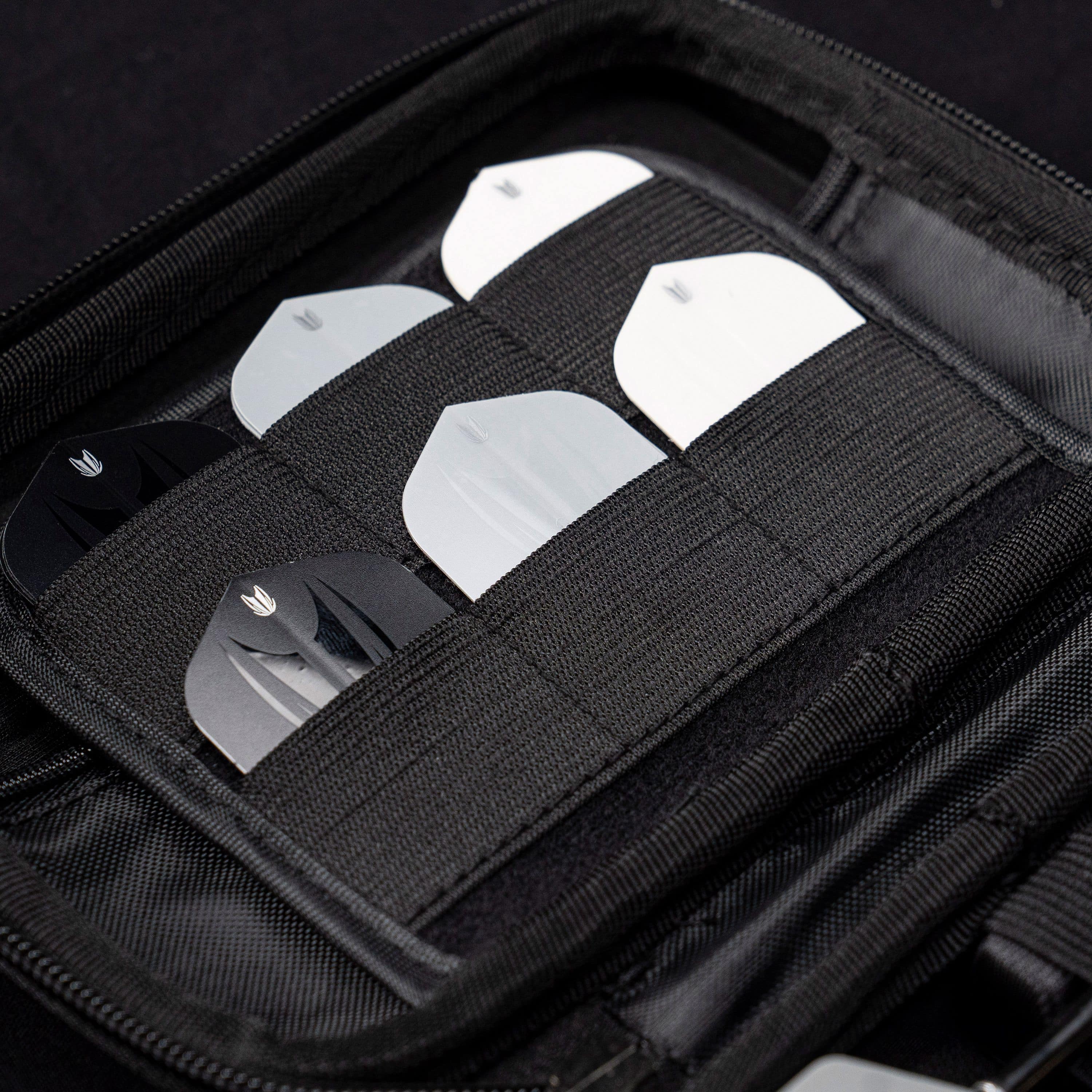 Étui à fléchettes Target Takoma Luke Littler Das Bild zeigt das Target Takoma Bolide Dartcase, in dem mehrere Dart-Flights ordentlich in elastischen Halterungen verstaut sind. Das Case ist schwarz und bietet sicheren Schutz für das Dartzubehör.