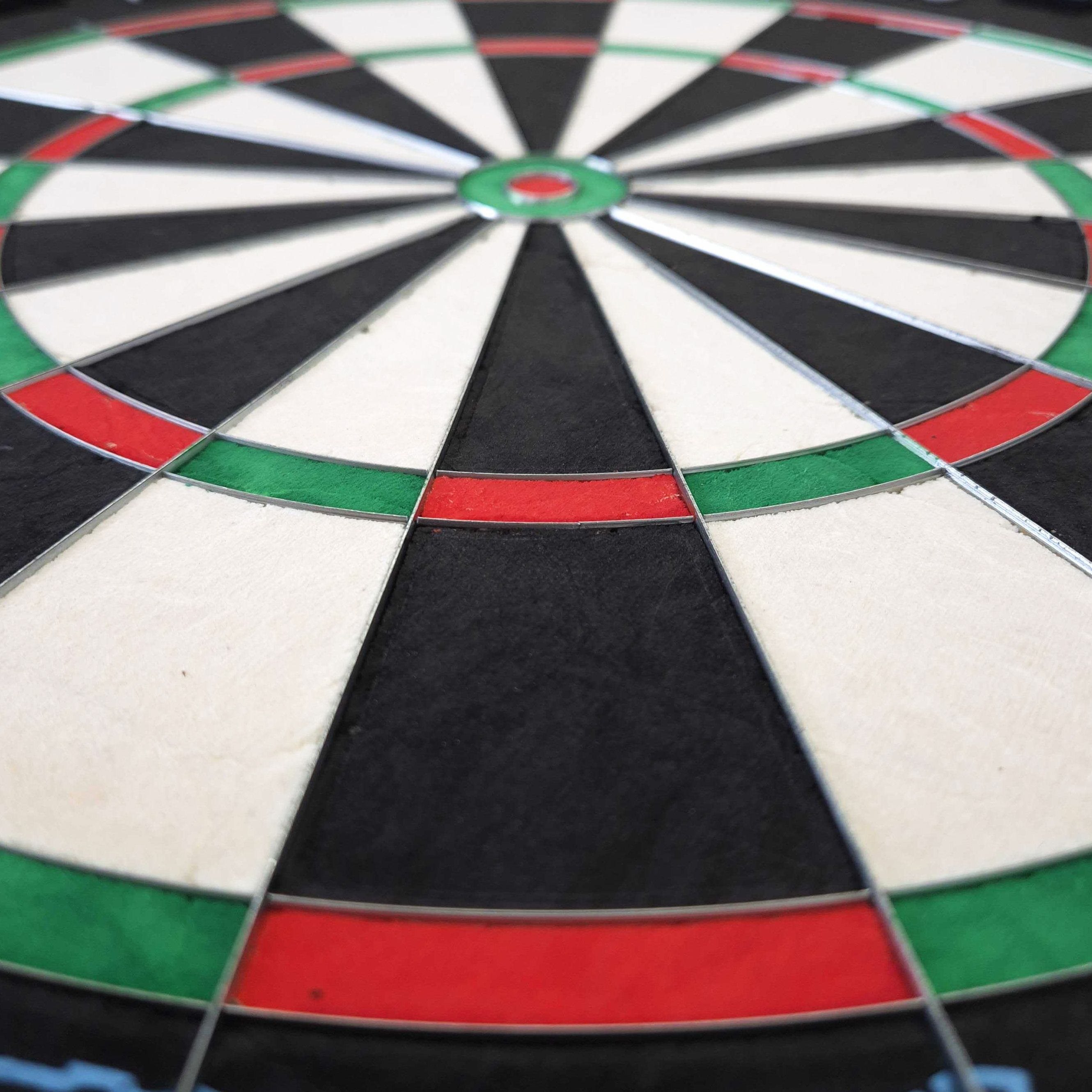 Cible de fléchettes en acier Mission Samurai Infinity Das Bild zeigt eine Nahaufnahme eines Steeldartboards mit klar erkennbaren Farbfeldern in Rot, Grün, Schwarz und Weiß. Es handelt sich um das Produkt "Mission Samurai Infinity Steeldartboard".