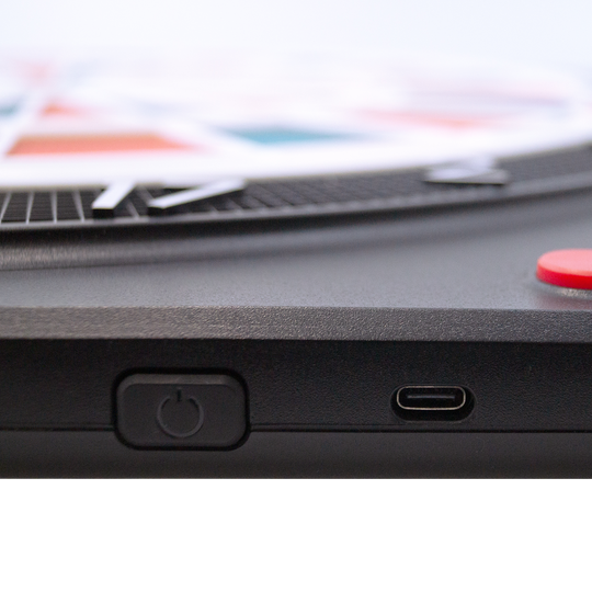Cible de fléchettes électronique souple Karella CB-Smart Das Bild zeigt einen Ausschnitt der Karella CB-Smart Elektronische Soft-Dartscheibe. Zu sehen sind der Ein-/Ausschalter und ein USB-C Anschluss an der Seite des Geräts.