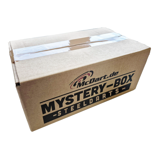 Boîte mystère McDart - Steeldarts Auf dem Bild ist ein Karton mit der Aufschrift "McDart.de Mystery-Box - Steeldarts" zu sehen. Die Box ist oben mit Klebeband verschlossen.