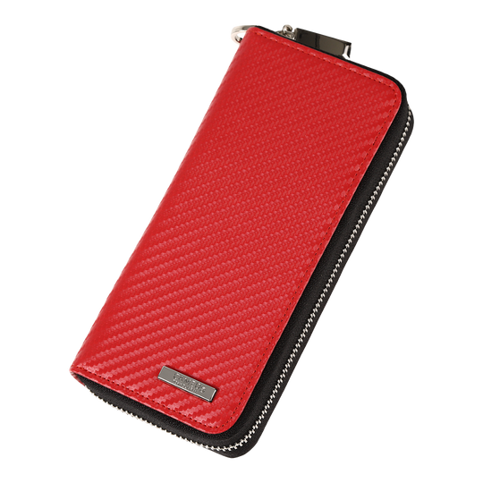 Das Bild zeigt ein rotes Etui mit einer strukturierten Oberfläche und einem Reißverschluss. An der unteren Ecke befindet sich ein kleines Metallschild mit einer Gravur.