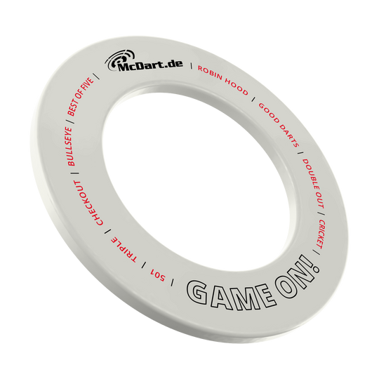 Das Bild zeigt einen weißen Dartboard-Surround-Ring mit der Aufschrift "McDart.de" und "GAME ON!". Auf dem Ring stehen außerdem in roter Schrift Begriffe rund um das Dartspiel wie "BULLSEYE", "TRIPLE", "CHECKOUT" und "CRICKET".