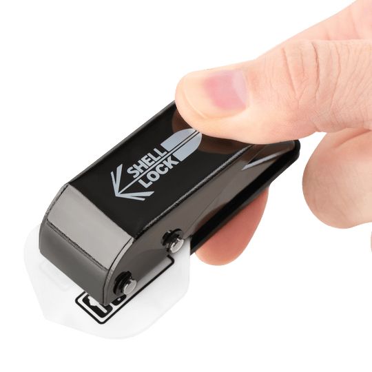 Poinçon de verrouillage de coque One80 style L Poinçon de vol Das Bild zeigt das Produkt "L-Style One80 Shell Lock Punch Flightlocher", das in einer Hand gehalten wird. Mit diesem Werkzeug wird ein Loch in ein Dartflight gestochen.