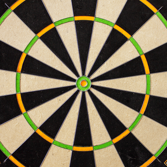 3023_Winmau_Champions_Choice_DualCore_Dartboard_31OalkqlJd5YsR Das Bild zeigt die Mitte eines Winmau Champions Choice DualCore Dartboards. Die Felder sind abwechselnd schwarz und weiß, mit grünen und orangefarbenen Ringen.